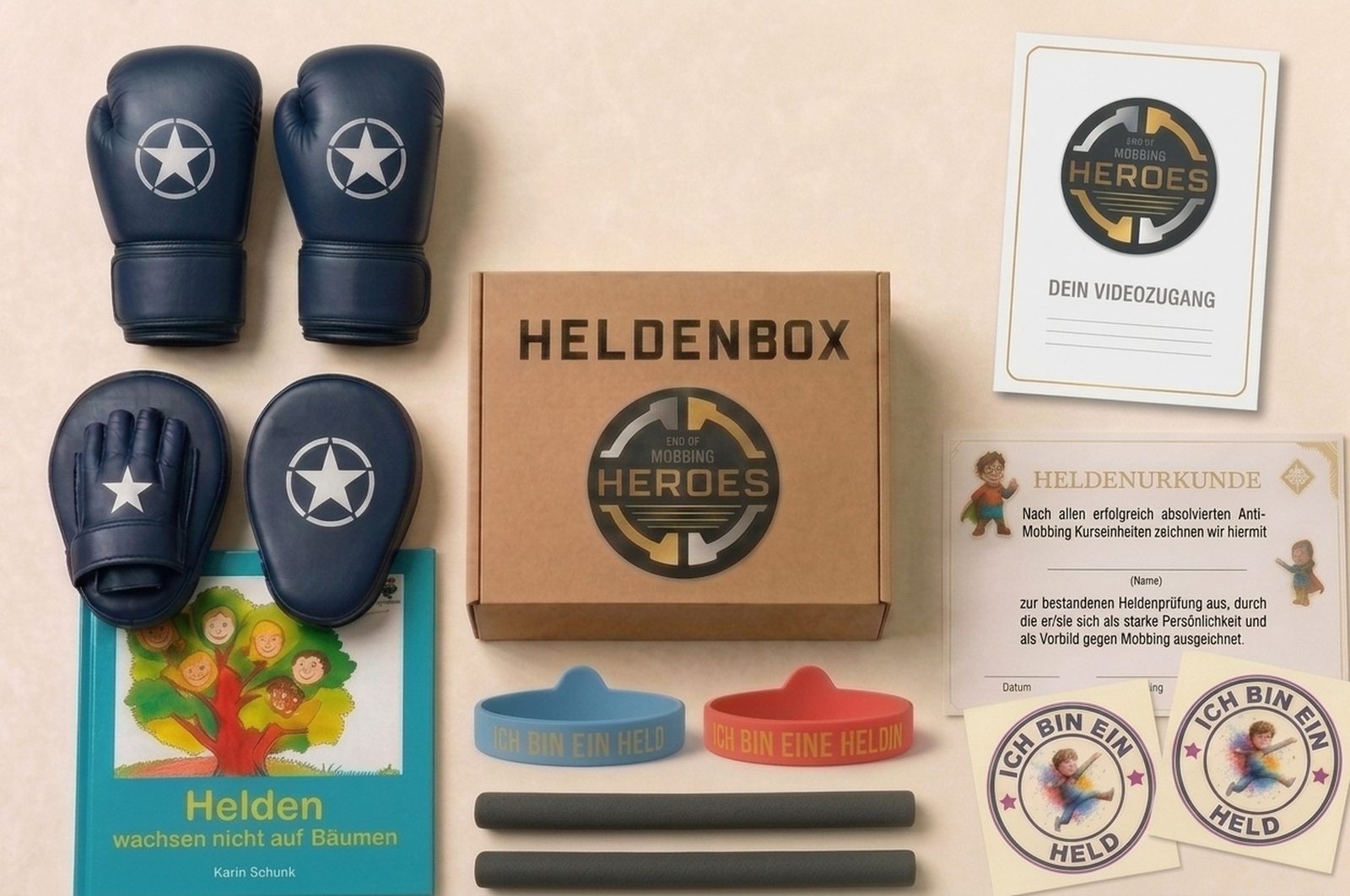 Der Inhalt der Heldenbox ausgebreitet: marineblaue Boxhandschuhe und Pratzen, zwei Trainingssticks, Heldenbuch, Urkunde, Heldenarmbänder in Blau und Rot, zwei Tattoos sowie die Karte für den Videozugang