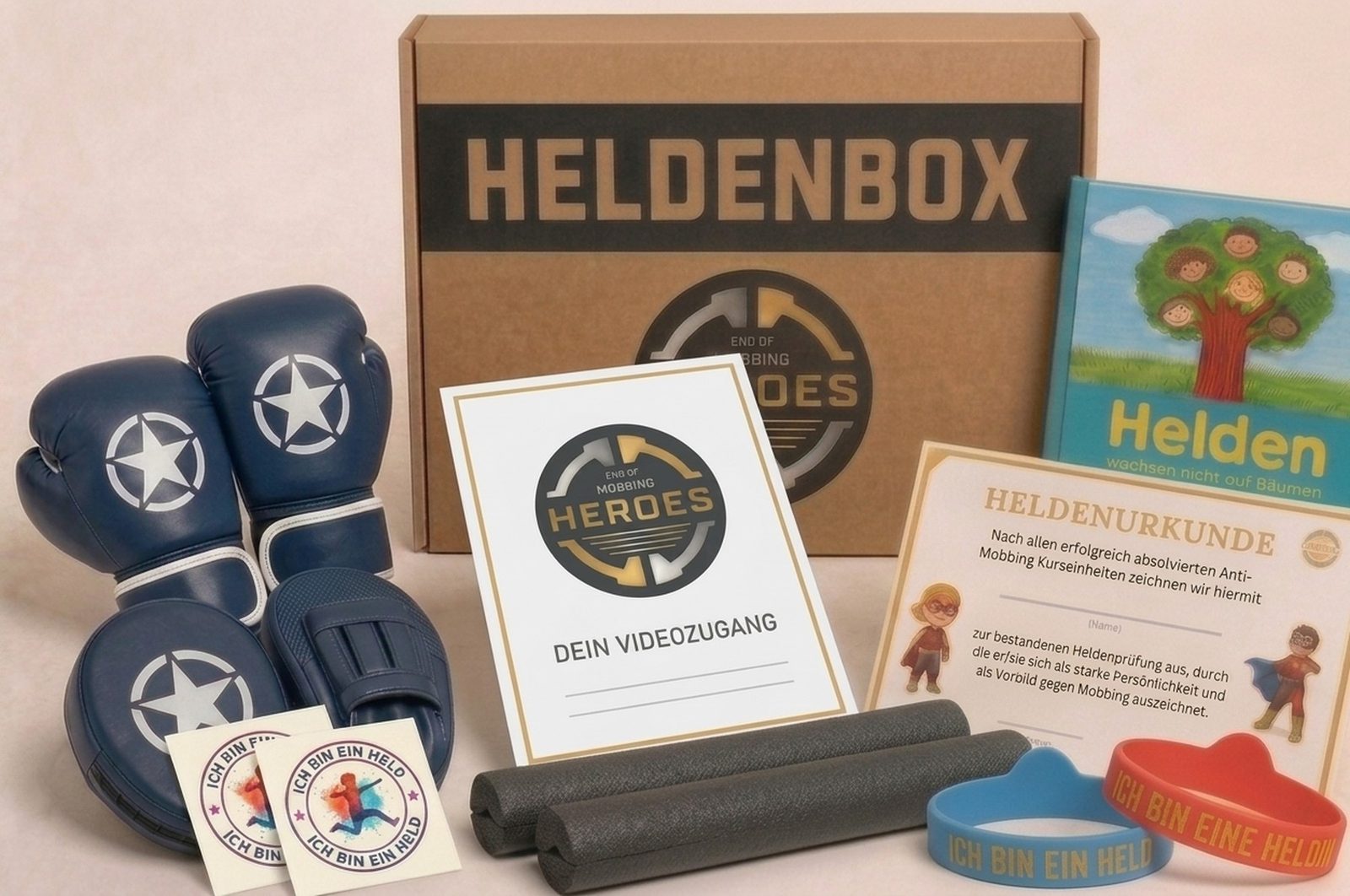Die echte Heldenbox von EOM Heroes: Naturkarton mit Logo, davor Boxhandschuhe, Pratzen, zwei Trainingssticks, Heldenbuch, Urkunde, Heldenarmbänder, Tattoos und die Karte für den Videozugang